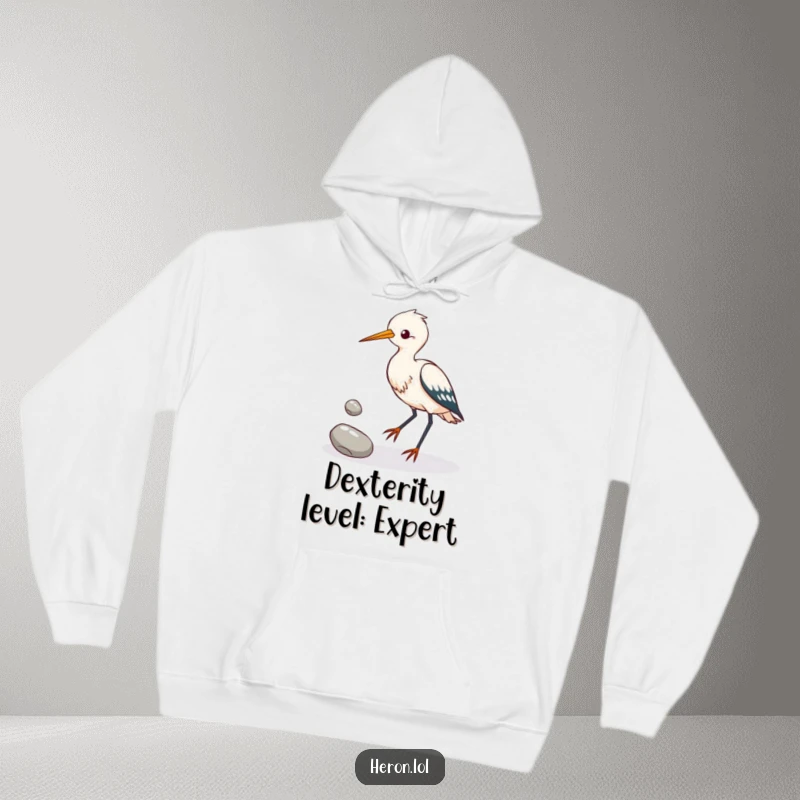 Funny heron bird attempting to juggle three shiny pebbles with its feet, featured on a cozy and humorous hoodie.